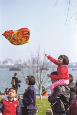 昨天是大年初一，天气晴好，西湖边游客爆满，白堤上人山人海，一个小女孩拿着卡通鸡气球坐在爸爸肩膀上。 - 浙江网