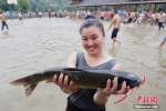 一名苗族姑娘展示抓到的草鱼。 谭凯兴 摄 - 浙江新闻网
