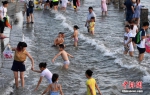 7月4日傍晚，市民们带着小孩在海边戏水消暑。张斌 摄 - 浙江新闻网