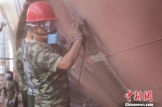 图为：官兵正“全副武装”对船体进行除漆作业。　张统纲 摄 - 浙江新闻网
