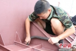 图为：即将退伍战士小张正在对压浪板进行清洁，准备打油漆。　何蒋勇 摄 - 浙江新闻网