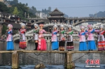 苗家姑娘走上古城内的木板桥进行服饰展示。 杨华峰 摄 - 浙江新闻网