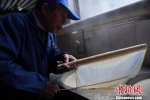 图为一位老人正在吹刚出锅的豆腐皮。　王刚　摄 - 浙江新闻网
