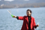 图为：一位女士正在西湖边玩泡沫。王刚 摄 - 浙江新闻网