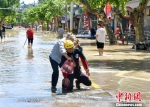 救援队队员背一位老人趟过积水后体力不支跪倒。　张煜欢 摄 - 浙江新闻网