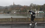 图为：一位游客戴口罩撑伞在断桥游览。 王刚 摄 - 浙江新闻网