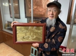 赵秀林举着一幅蕴含绍兴风光的铜雕作品。　项菁 摄 - 浙江新闻网