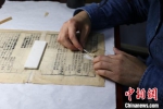 在浙江图书馆，古籍修复师用镊子小心揭下旧纸片。　童笑雨　摄 - 浙江网